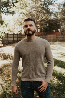Rob Wearing a Sweater in a backyard, with a fence in the background
